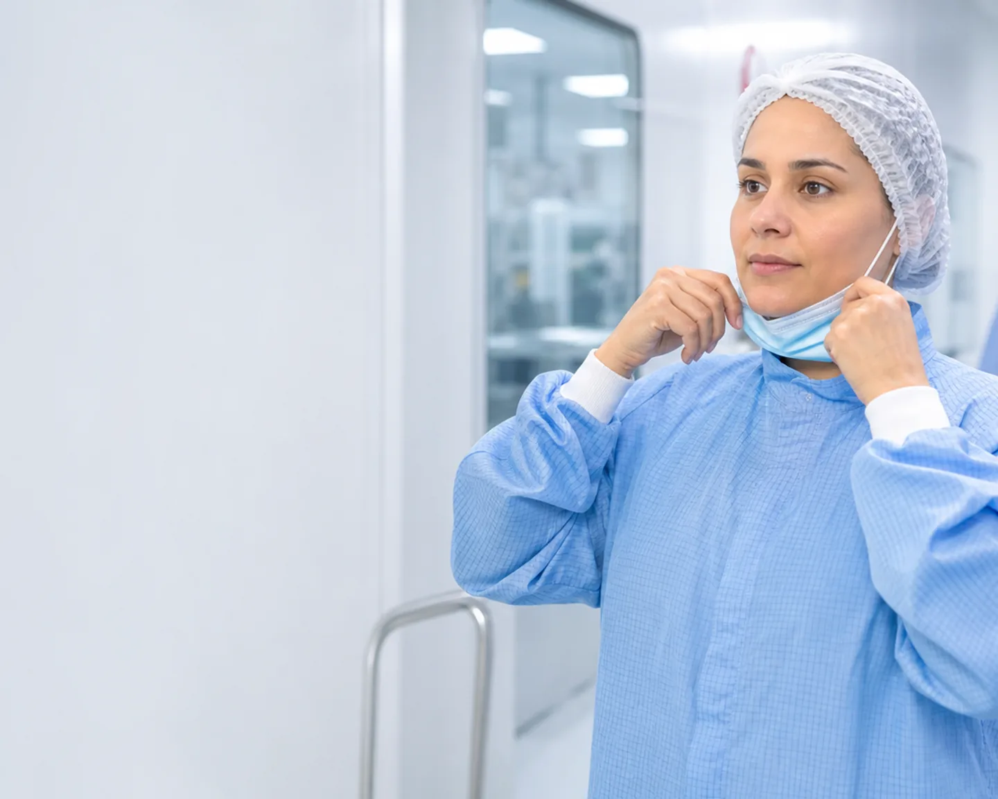 Trabalhadora realizando paramentação para entrar em área limpa farmacêutica